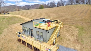 A two-story house with a deck, a hot tub, and outdoor seating.