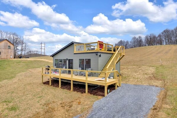 A small cabin with a wooden deck and a staircase leading to a balcony.