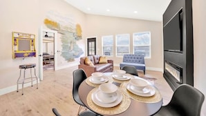 A modern living room with a dining area, a fireplace, and a large window.