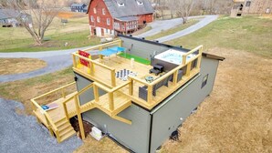 A small cabin with a wooden deck, a hot tub, and a ping pong table.