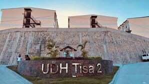 A large building with a sign reading "UDH Tisa 2" and a small pavilion in front.