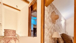 A room with a wooden table, a white vase, a woven basket, a lamp, and a sofa with patterned cushions. - Charming Gîte in the Heart of Beaujolais (Lancié)