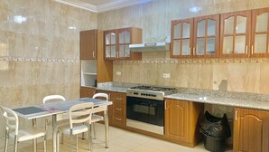 Una cucina con piano cottura a gas, forno, mobili in legno e un tavolo da pranzo con sedie.