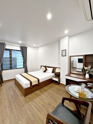 Una habitación de hotel con una cama, mesita de noche, lámpara y una pequeña mesa redonda con una bandeja.