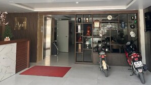 A modern building entrance with a reception desk, a red carpet, and two motorcycles parked outside. - Au79 Hotel & Apartment (Hai Phong)