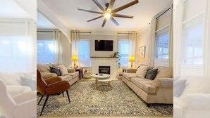 A living room with a ceiling fan, two sofas, a coffee table, and a fireplace. - Sweet Magnolia, 3Br/2.5Ba, Downtown Historic Charm w/ all the comforts!  (Orlando)