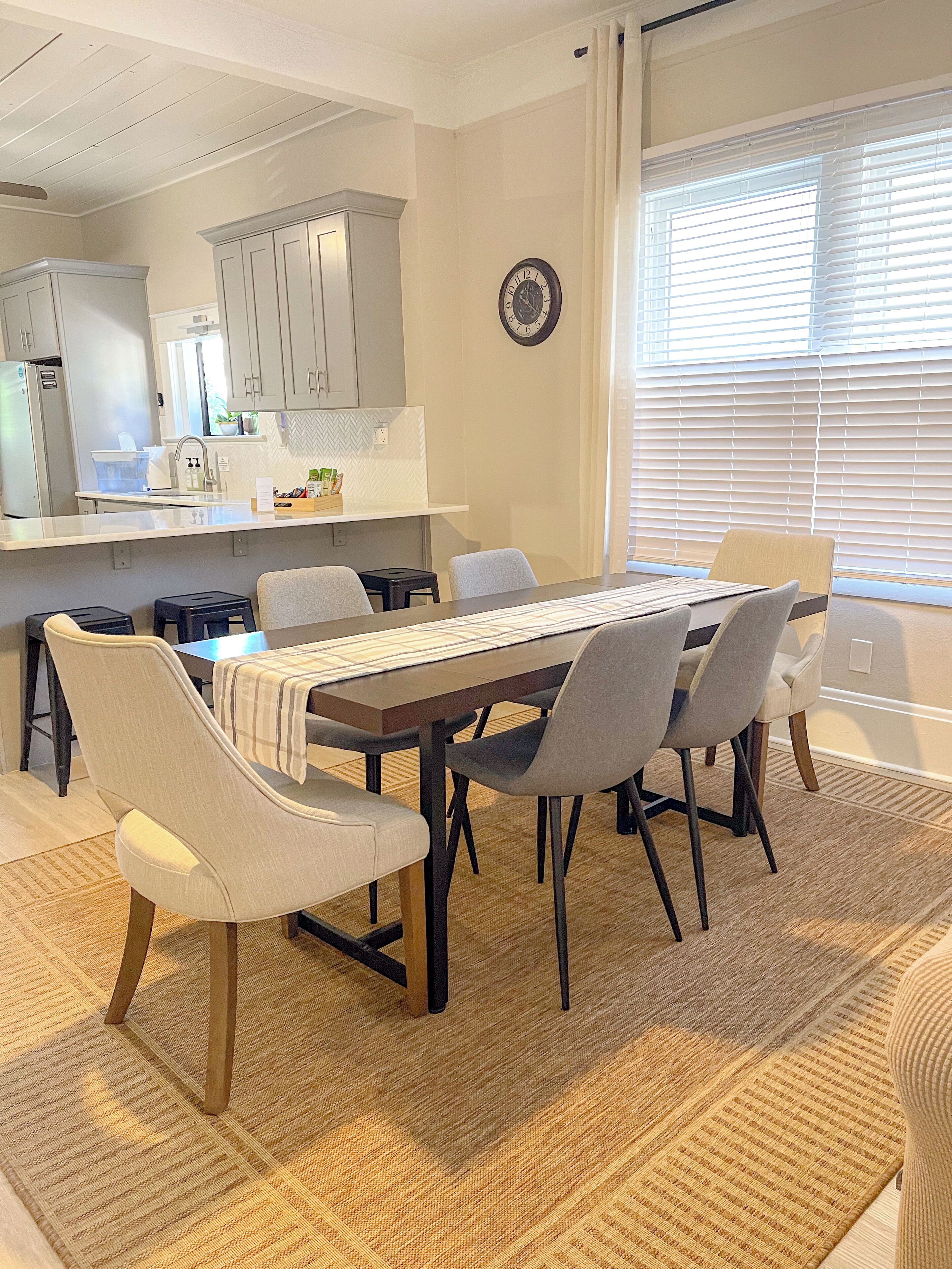A modern kitchen with white cabinets, a built-in oven, and a window with blinds.