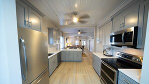 A modern kitchen with stainless steel appliances, light wood flooring, and a central island. - Sweet Magnolia, 3Br/2.5Ba, Downtown Historic Charm w/ all the comforts!  (Orlando)