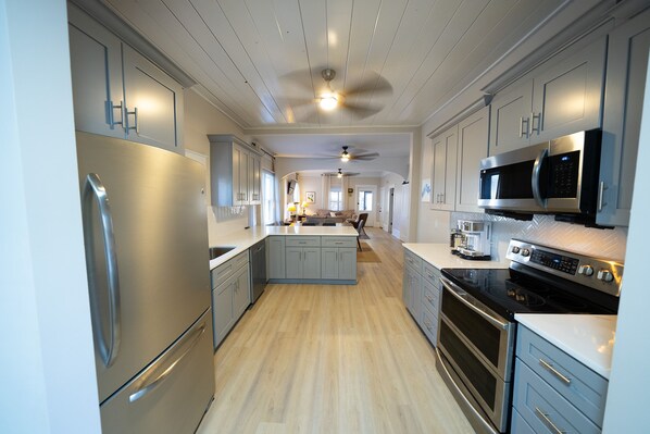 A modern kitchen with stainless steel appliances, light wood flooring, and a central island.