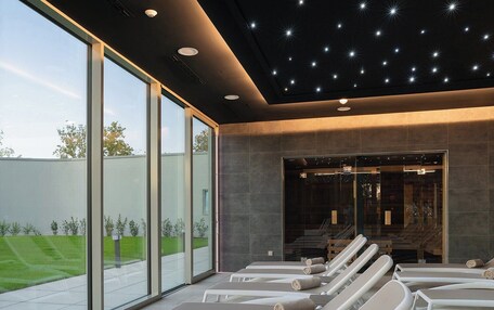 A modern spa area with sun loungers, large windows, and a starry ceiling.