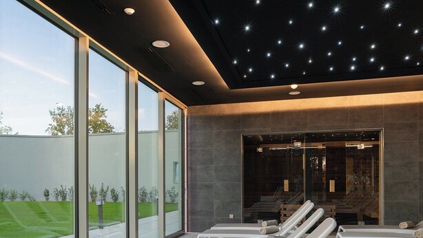 Un'area benessere moderna con sdraio, ampie vetrate e un soffitto a stella.
