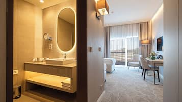 Un baño de hotel moderno con un espejo grande, lavamanos dobles y tocador.