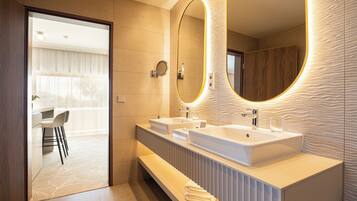 A modern bathroom with two sinks, a large mirror, and a vanity with a towel rack.