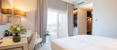 Una habitación de hotel con cama, escritorio, silla y una mesita con un florero.