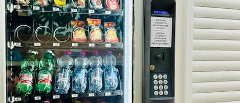 Máquina expendedora con una variedad de aperitivos y bebidas, incluyendo bebidas energéticas y refrescos.
