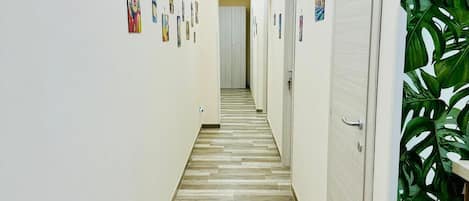 A hallway with a patterned floor, white walls, and artwork.
