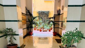 A hotel lobby with a central seating area, potted plants, and a tiled floor. - punto house ferrovia (Naples)