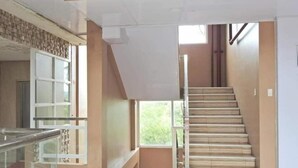 A modern interior with a staircase, a glass railing, and a view of greenery outside. - Grandview Residences by Vilma near Burnham Park-204 (Baguio)