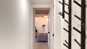Corredor que leva a uma sala de estar com sofá e abajur.