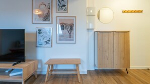 Una sala moderna con un banco de madera, un televisor y obras de arte enmarcadas en la pared.