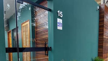 Un bâtiment moderne avec une entrée en verre, portant le numéro 15, et une petite pancarte indiquant une zone de service ouverte 24 heures sur 24.
