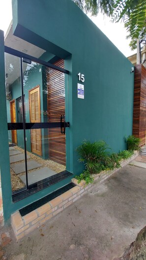 A modern building with a glass door entrance, numbered 15, and a small sign indicating a 24-hour service area. - Morada do Sol Suítes (Arraial do Cabo)