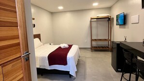 A hotel room with a bed, a desk, a chair, a TV, and a wardrobe. - Morada do Sol Suítes (Arraial do Cabo)