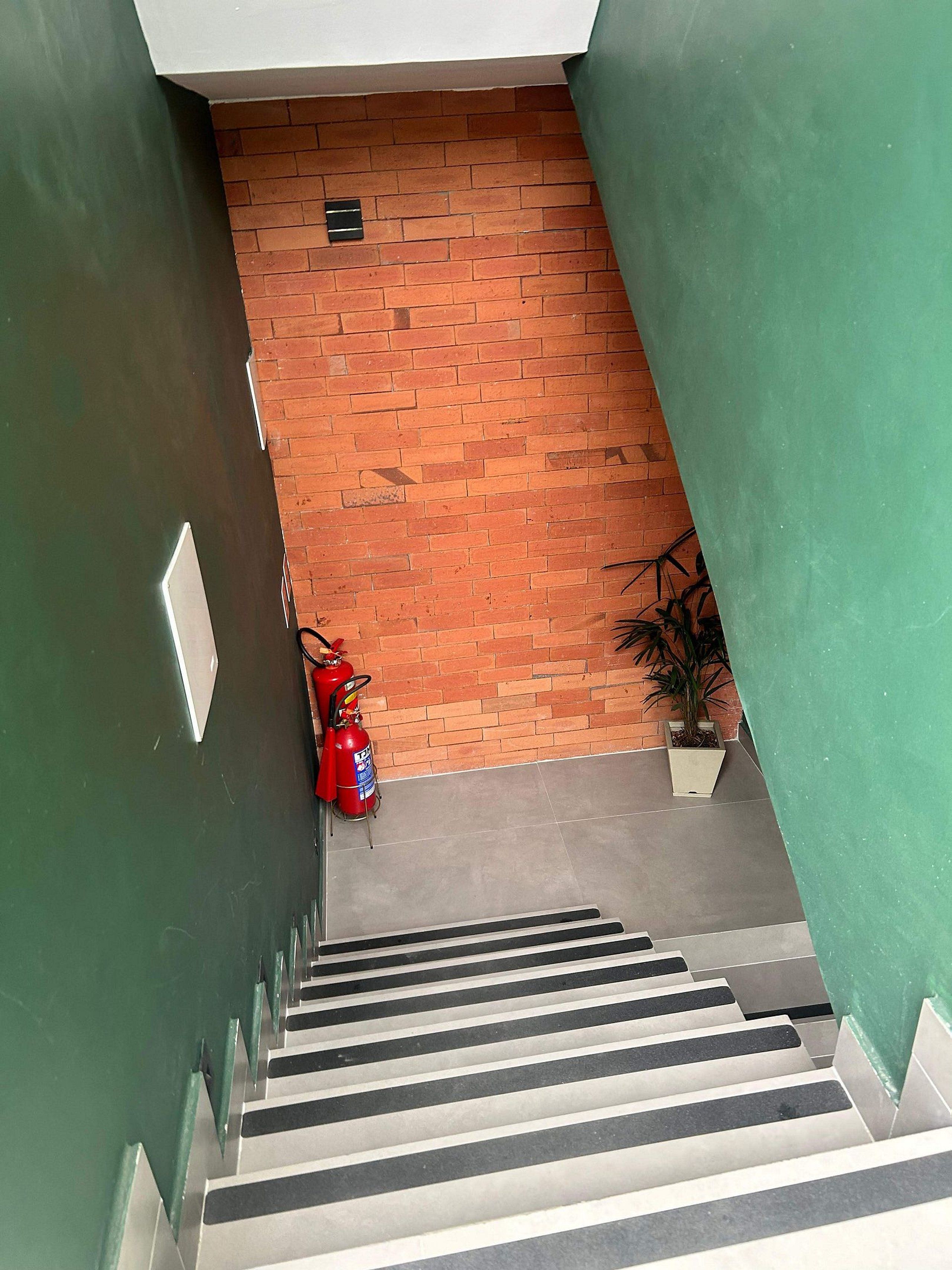 A staircase with a fire extinguisher and a potted plant at the bottom.