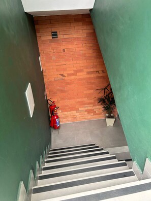 A staircase with a fire extinguisher and a potted plant at the bottom. - Morada do Sol Suítes (Arraial do Cabo)