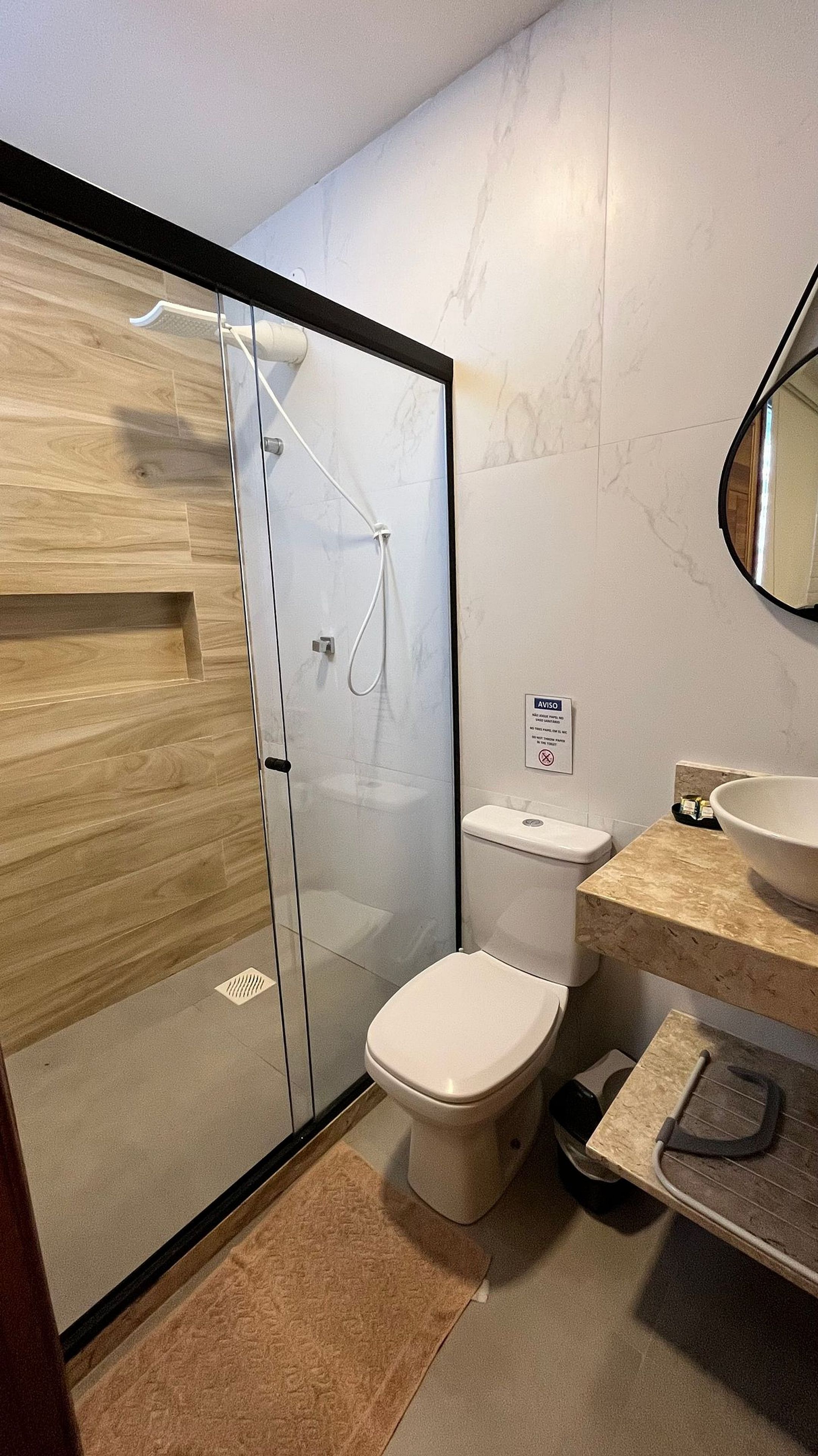 Une salle de bain moderne avec une douche à l’italienne en verre, des toilettes et un lavabo doté d’un plan de travail en marbre.