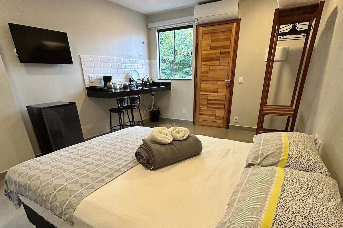 A bedroom with a bed, a desk, and a TV.