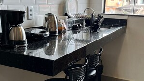 A kitchen with a microwave, coffee maker, and bar stools. - Morada do Sol Suítes (Arraial do Cabo)