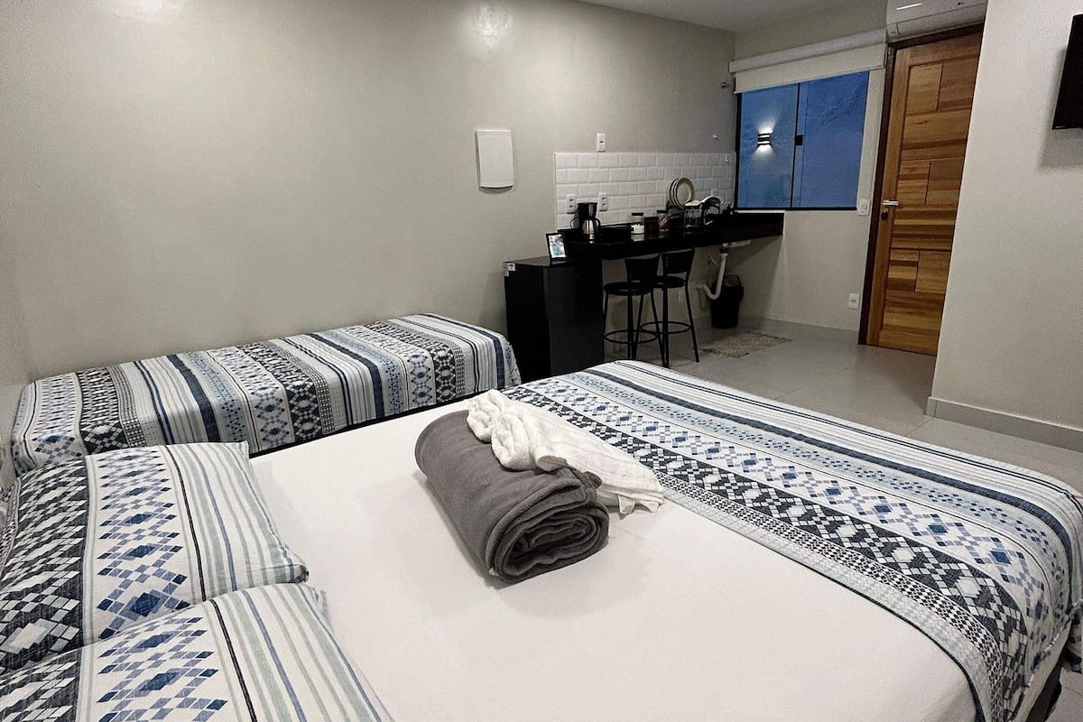 A hotel room with a large bed, a desk, and a kitchenette.