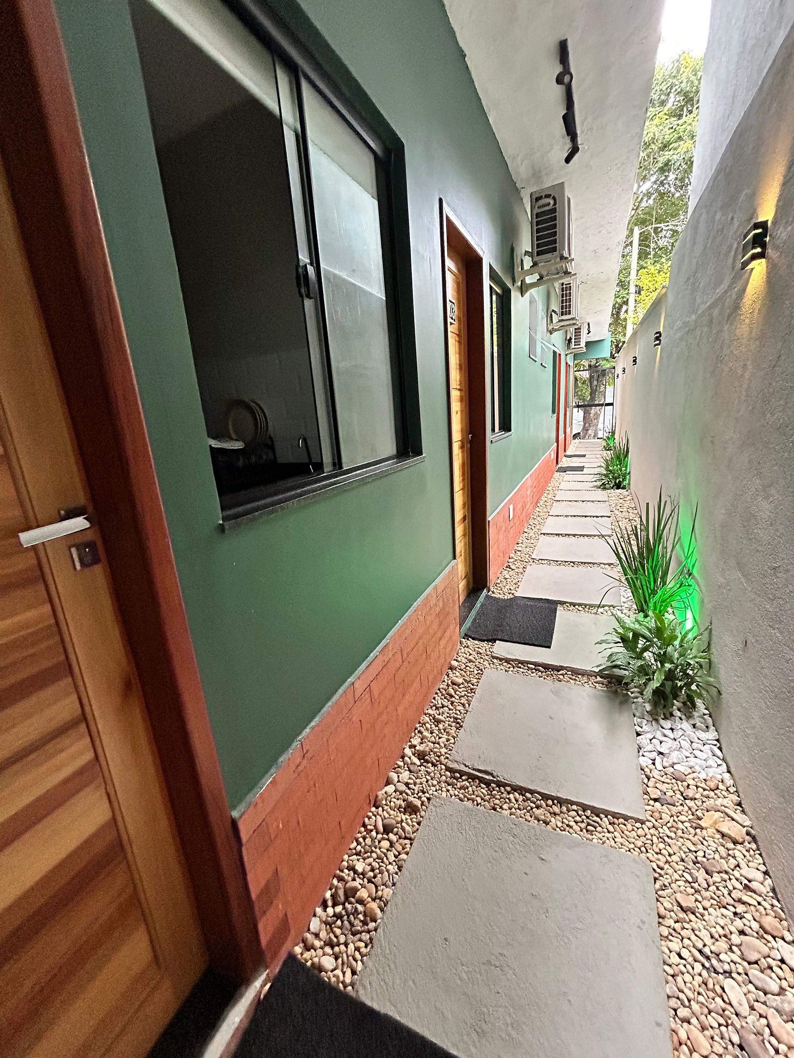 A narrow hallway with a green wall, wooden door, and a window.