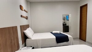 A hotel room with a bed, a bedside table, a mirror, and a wardrobe. - Morada do Sol Suítes (Arraial do Cabo)
