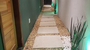 A narrow hallway with a pebble path, wooden door, and green walls. - Morada do Sol Suítes (Arraial do Cabo)