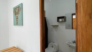 Un baño con inodoro, lavamanos y una banca de madera.