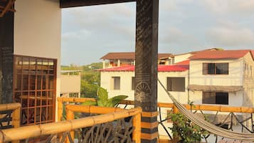 Una terraza de madera con una hamaca, una mesa de madera y una planta en maceta.