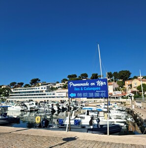 A marina with boats docked, a sign for 'Promenade en Mer,' and a building labeled 'BLEU' in the background. - Belle Maison Avec Vue mer et Port (Carry-le-Rouet)