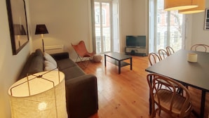 Ein modernes Wohnzimmer mit einer Couch, einem Fernseher, einem Esstisch und Stühlen.