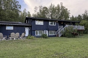 A two-story house with a deck, outdoor seating, and a staircase leading to the upper level. - Escape to a private hilltop luxury home with breathtaking valley & Aurora views! (Fairbanks)