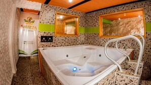 A bathroom with a stone mosaic wall, a wooden ceiling, a bathtub, and a mirror. - Glamping Experience Savieza (Nemocon)