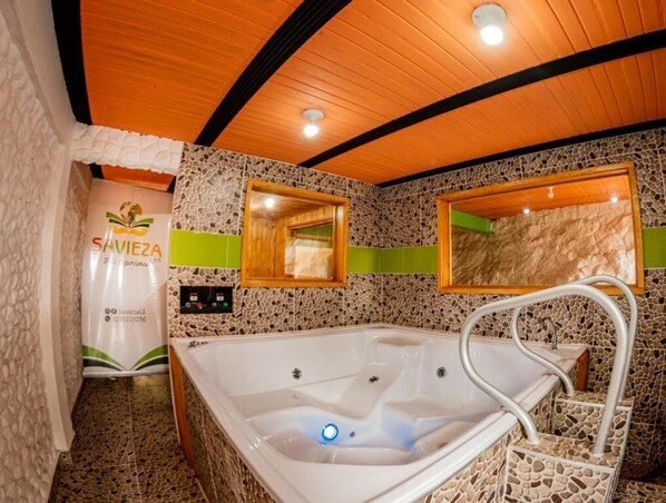 A bathroom with a stone mosaic wall, a wooden ceiling, a bathtub, and a mirror.