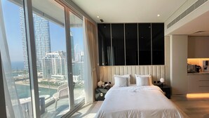 Ein modernes Hotelzimmer mit einem großen Bett, Blick auf eine Stadtlandschaft und einem Balkon.