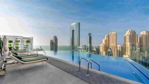 Ein Pool auf dem Dach mit Liegestühlen und Blick auf die Skyline der Stadt.