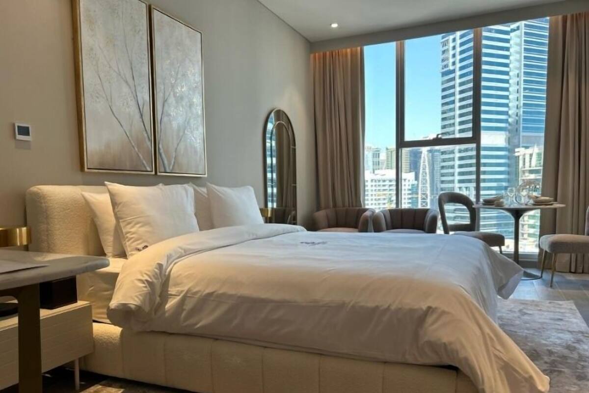 Ein modernes Hotelzimmer mit einem großen Bett, einem Schreibtisch und Blick auf hohe Gebäude.