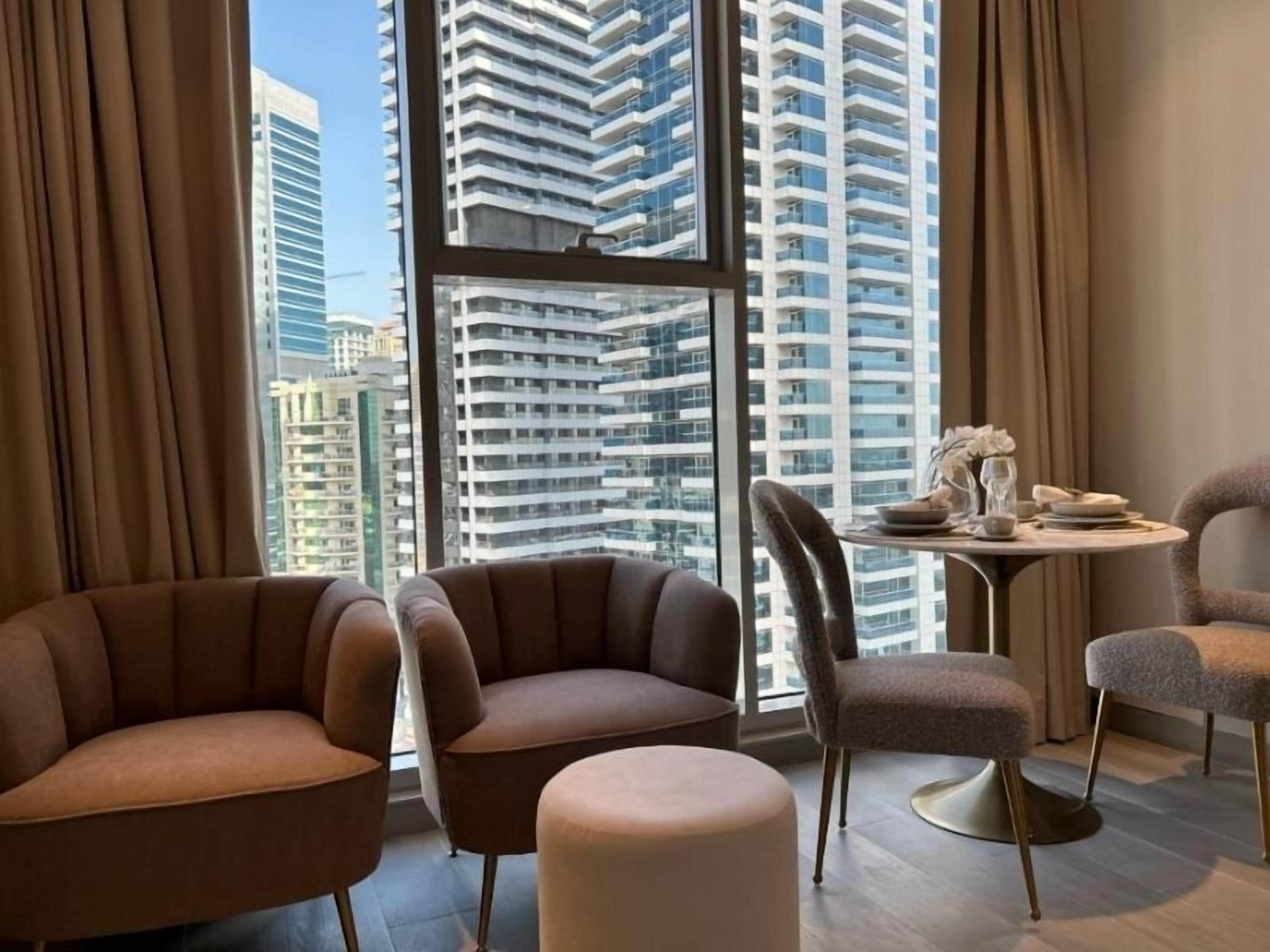 A modern hotel room with a large window, two sofas, a small round table, and a decorative vase.