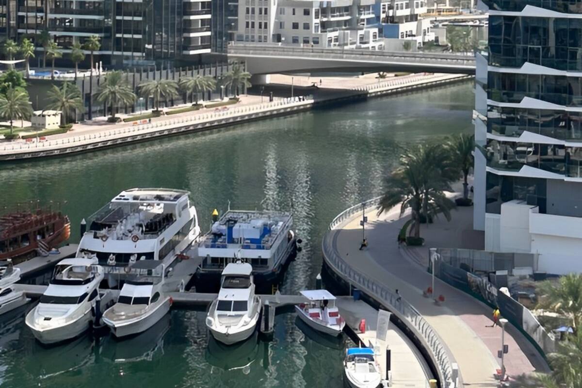Ein Yachthafen mit mehreren vertäuten Booten, umgeben von Hochhäusern und einem Fluss.
