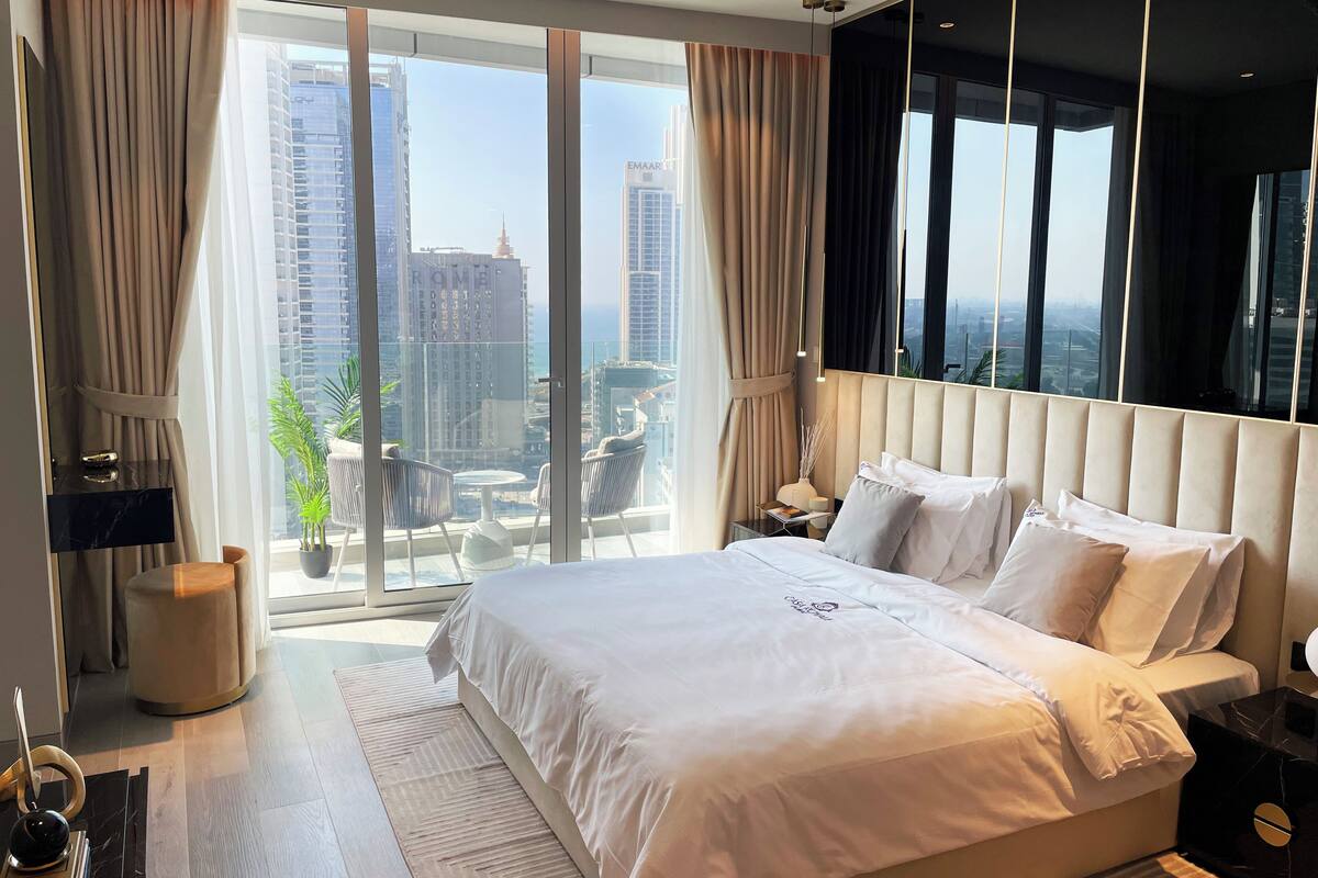Ein modernes Hotelzimmer mit einem großen Bett, einem Nachttisch, einem kleinen Tisch und Blick auf die Stadt.