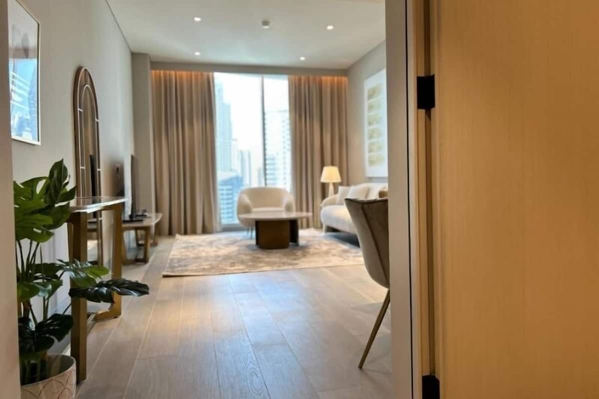 Ein modernes Hotelzimmer mit großem Fenster, einer Couch, einem Couchtisch und einem Blumentopf.